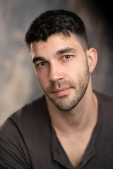 Obraz premium Handsome caucasian white male with black short hair and stubble with brown t shirt