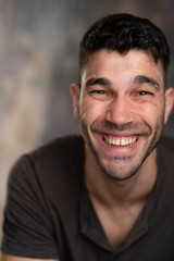 Fototapeta premium Handsome caucasian white male with black short hair and stubble with brown t shirt laughing hilariously