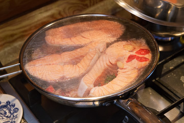 Salmon fillet on frying pan.  Salmon steaks with vegetables roasting on frying pan. Cooking.