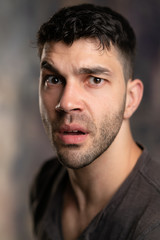 Fototapeta premium Handsome caucasian white male with black short hair and stubble with brown t shirt looking confused