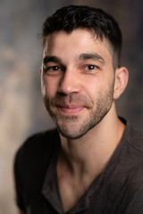 Fototapeta premium Handsome caucasian white male with black short hair and stubble with brown t shirt, cheeky smile