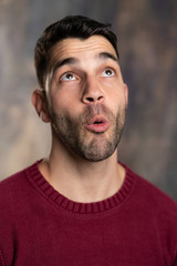 Fototapeta premium Handsome caucasian white male with black short hair and stubble and burgundy sweater jersey in awe