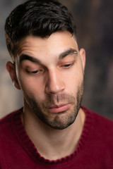 Obraz premium Handsome caucasian white male with black short hair and stubble and burgundy sweater jersey, silly face