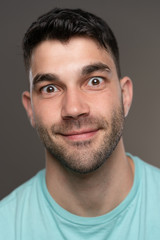 Obraz premium Handsome caucasian white male with black short hair and stubble with light blue t shirt