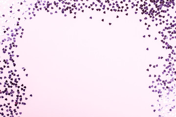Flat lay top view  glitter confettiin the shape of a heart on pink background. .Greeting card Festive holiday pastel backdrop Love. Birthday congratulations St. Valentine's Day .Copy space for Text