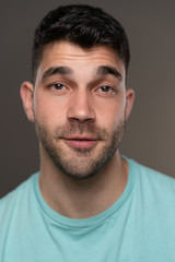 Obraz premium Handsome caucasian white male with black short hair and stubble with light blue t shirt