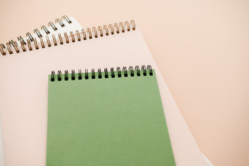 Stationary concept, Flat Lay top view Photo of notepads  on beige background with copy space.Creative flat lay photo of workspace desk with  white and green notebooks minimal style. 