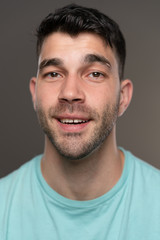 Fototapeta premium Handsome caucasian white male with black short hair and stubble with light blue t shirt