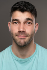 Obraz premium Handsome caucasian white male with black short hair and stubble with light blue t shirt