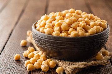 Chickpeas in ceramic bowl on dark wooden rustic table. Selective focus.