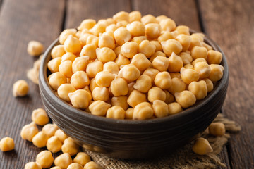 Chickpeas in ceramic bowl on dark wooden rustic table. Selective focus.