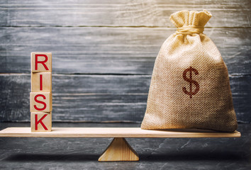 Money bag and wooden blocks with the word Risk. The concept of financial risk. Justified risks. Investing in a business project. Making the right decision. Property insurance. Legal and market risks - obrazy, fototapety, plakaty