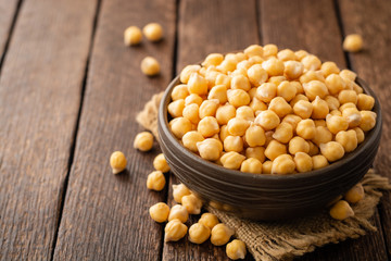Chickpeas in ceramic bowl on dark wooden rustic table. Selective focus.