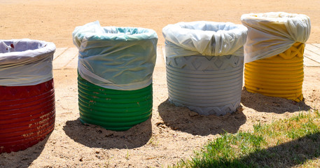 Four containers for garbage sorting and recycling, garbage containers for paper, glass, plastic and metal on the beach