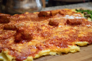 Cooking polenta, typical, traditional, Italian food made with cornmeal and water. Polenta topped with vegetables, sausage and pork with gravy, on wooden pastry. Lunch at home with the family.