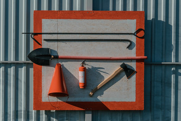 Red fire stand with fire extinguishing tools: conical fire buckets, fire ax, hook and spade hanging