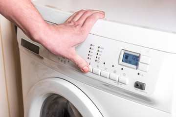 Woman select the program on washing machine. Laundry day at home. 