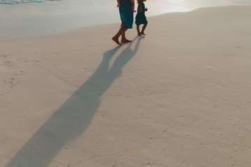 mother with kids walk on sunset beach