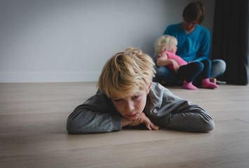 siblings rivalry- sad son and dad holding baby daughter