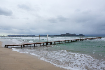 Steg am Strand wird von grün blauen Wellen umspült, copy space unten