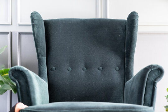 Close up high back green velvet armchair with gray painted wall in the background / interior concept / empty space for advertising