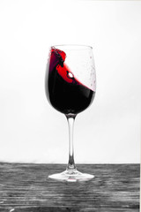 Red wine in the glass splashes in motion on a white background. Design card