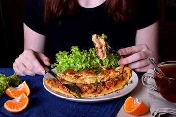 Woman is eating a piece of omelette with a fork. Breakfast meal