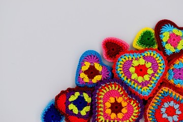 Knitted hearts from a multi-colored yarn on a white background. Valentine's Day, love, handmade, amigurumi, hobby, decoration, postcard, creative.