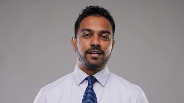 business, communication and people concept - indian businessman having video conference or interview and talking over grey background