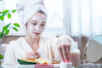 Beautiful happy young woman with natural cosmetic mask on her face. Skin care and Spa treatments at home