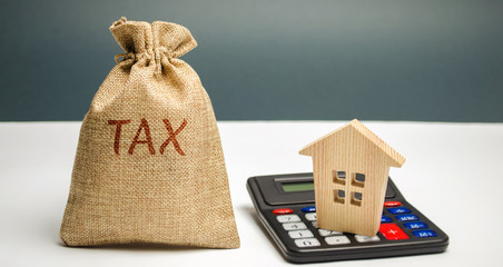 A bag with the word Tax and calculator with a house. Taxes on real estate, payment. Penalty,...