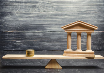 A miniature bank and money on the scales. The concept of successful investment in the bank. Credit...