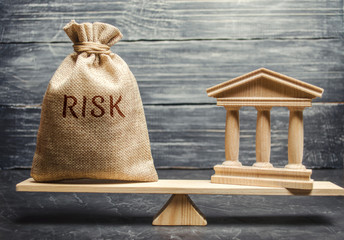 A money bag with the word Risk and a bank building on the scales. The concept of financial and...