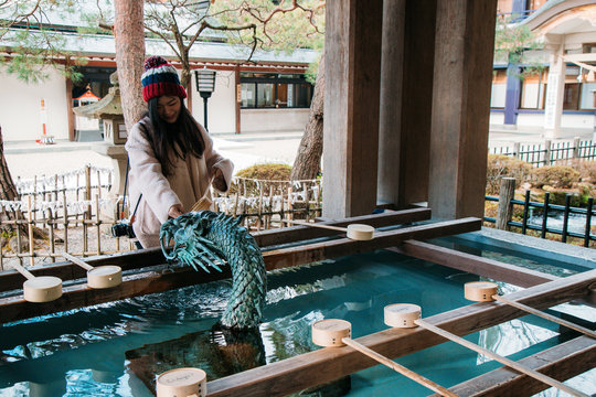 Asia girl scoop water from Suijin pond at Sakurayama Hachimangu Shrine.  Suijin (water god) is the Shinto god of water in Japan. Stock Photo | Adobe  Stock