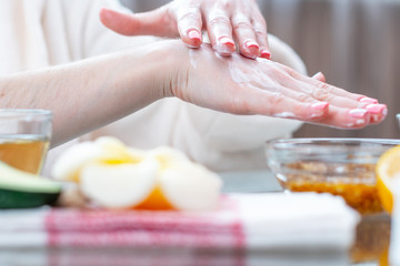 Woman applying the cream on her hands nourishing them with natural cosmetics close-up. Hygiene and care for the skin