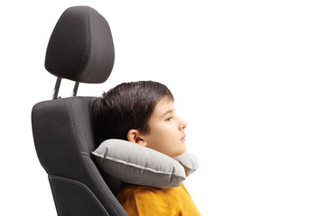 Boy in a car seat with a travel pillow around his neck