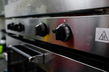 Close up of oven knob on metal board dial of a stainless steel electric oven