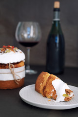 Easter cake and glass of red wine. Easter composition with orthodox sweet bread, kulich and bottle of wine on dark background. Easter holidays breakfast
