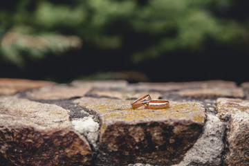 Golden wedding rings on the old stone bridge 