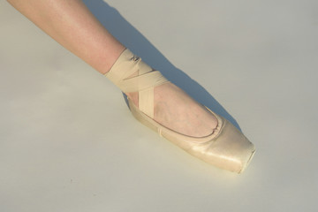 Toe dancing. Ballerina leg in white ballet shoe. Lacing ballet slipper. Female foott in pointe shoe. Pointe shoe worn by ballet dancer. Classic dance style. Ballerina shoe. Concert dance performance © Volodymyr
