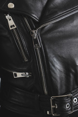 Black leather jackets with metallic zipper and buttons. Classic clothes for biker. Detailed vertical closeup view.