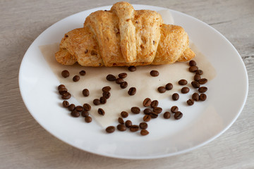 croissant and coffee beans on a white plate