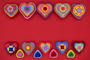 Knitted hearts on a red background. Handmade, amigurumi hobby, love, Valentine's Day, decoration, design.