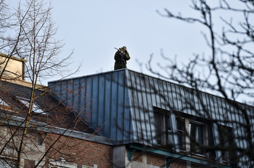 sniper securing a perimeter from a rooftop