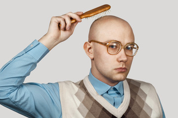 bald man with alopecia combing his head with a comb. joke concept