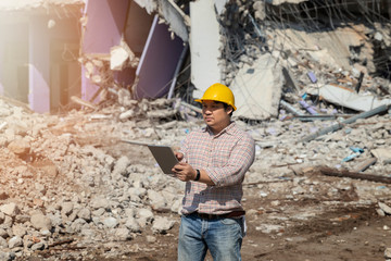 Engineer holding tablet is checking for destruction, demolishing building.