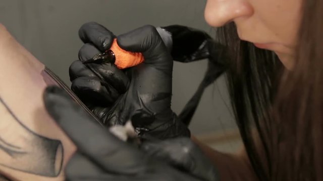 Beautiful female tattoo artist makes tattoo on hand of the client, camera moving