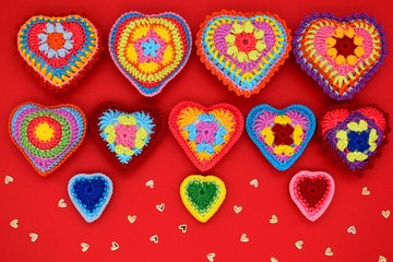 Fototapeta premium Knitted hearts on a red background. Handmade, amigurumi hobby, love, Valentine's Day, decoration, design.