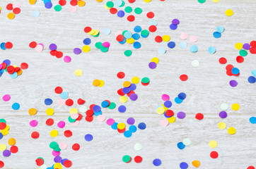 Confetti, colorful and round, on wood - background for carnival, New Year's Eve