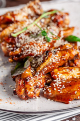 American cuisine concept. Fried glazed chicken legs with sesame on a white plate with chilli peppers. Background image for a menu in restaurants or cafes. copy space